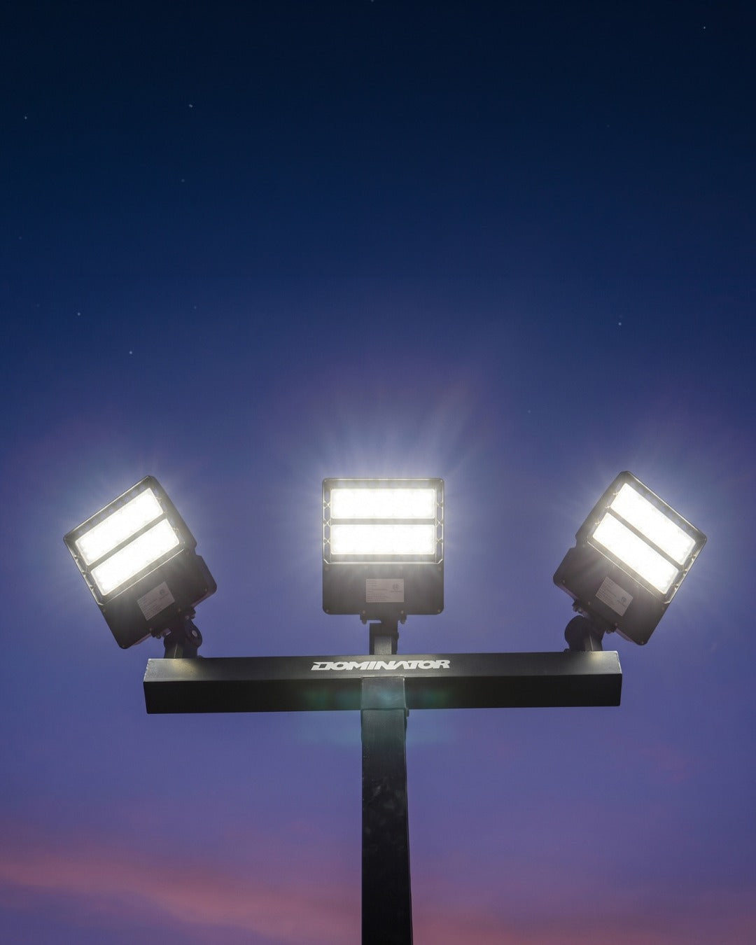 Illuminated Dominator court light fixtures at dusk