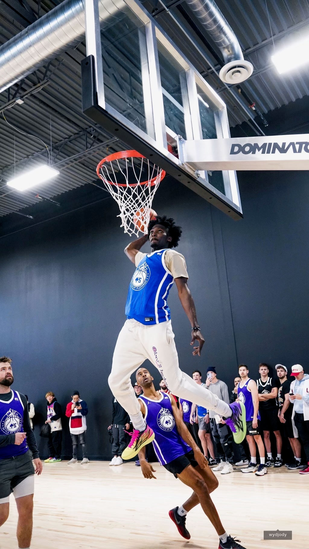 A basketball player rises to dunk on a Dominator hoop during a game