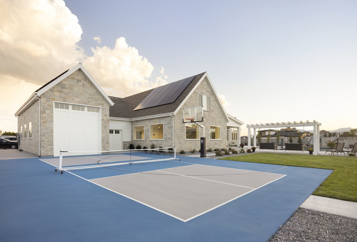 A finished backyard court with a Dominator basketball hoop and pickleball net
