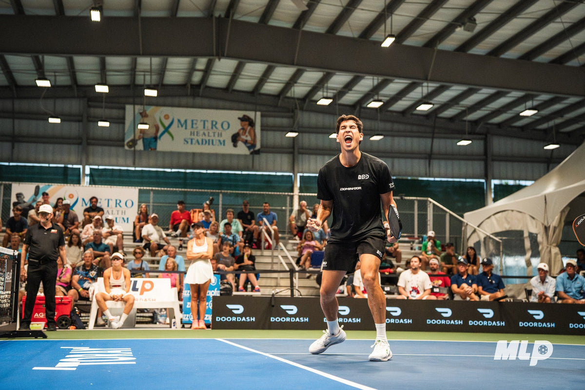 An athlete in a Dominator shirt celebrates during a pickleball tournament